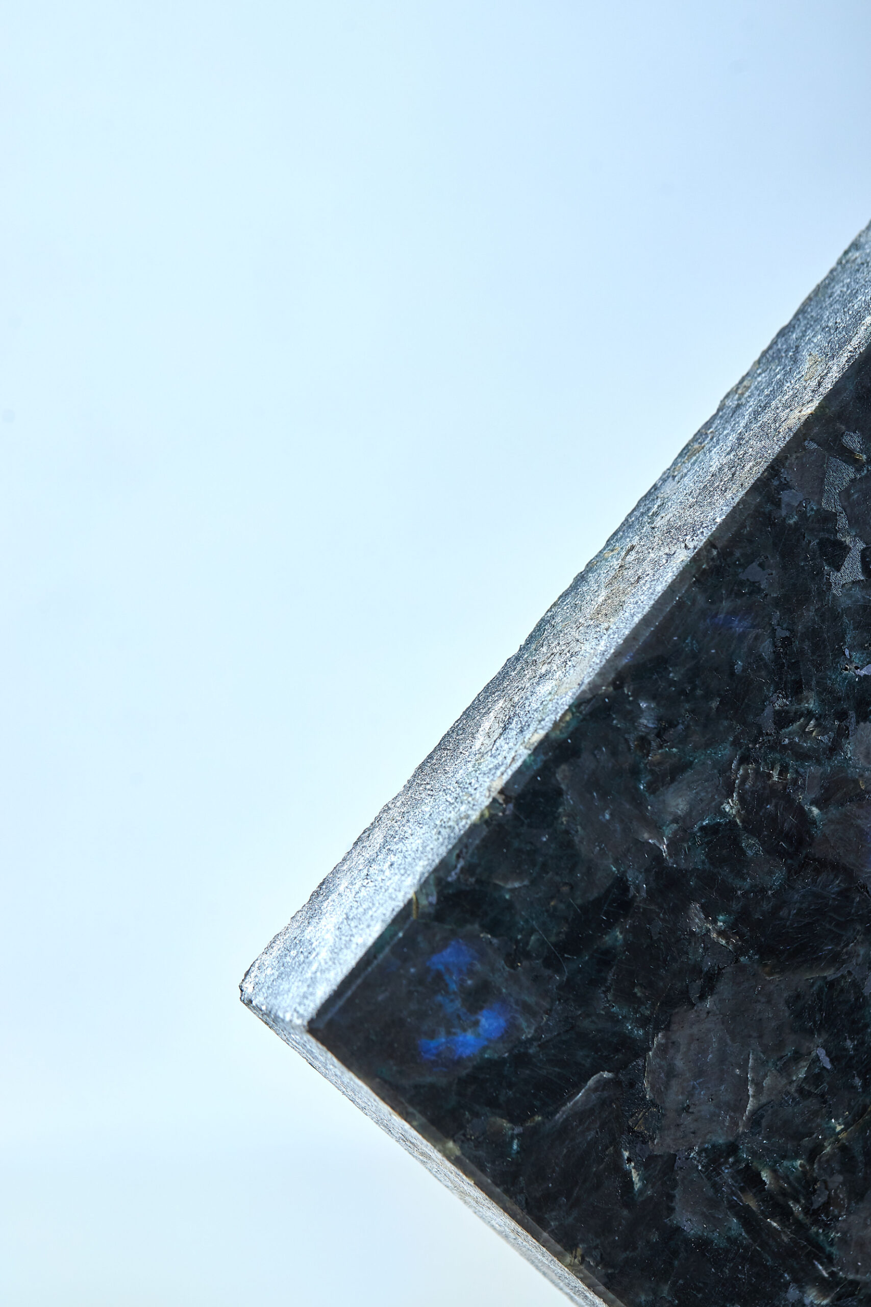 Close-up fragment of labradorite with a dark crystalline surface and natural blue flashes