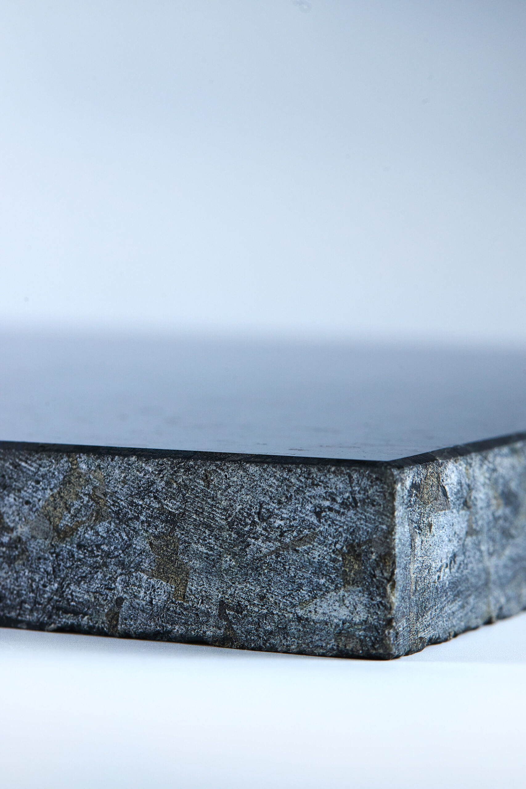 Labradorite sample on a light background with a dark crystalline structure and natural blue flashes